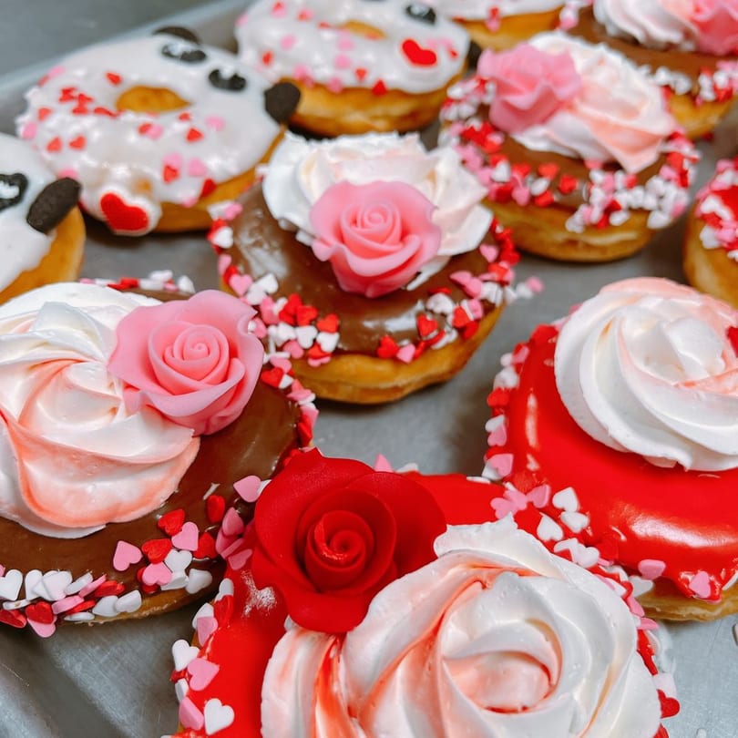 Valentine's donuts with buttercream swirls and fondant roses on a tray.