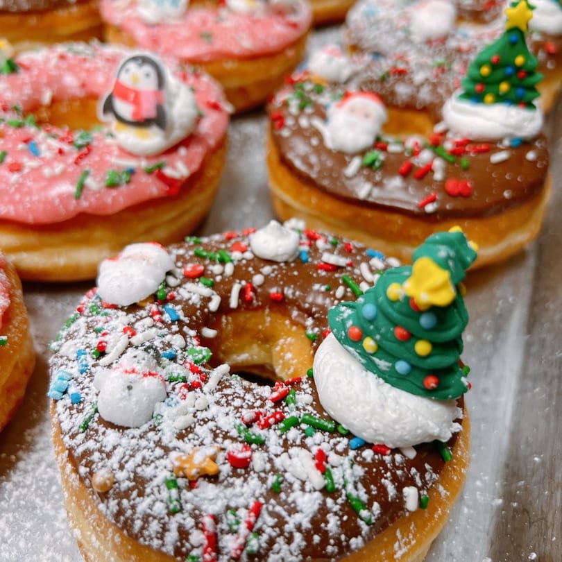 Christmas donuts with powdered sugar, holiday sprinkles, and fondant tree and Santa toppers.
